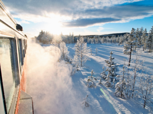 Tåg på Inlandsbanan, snö yr och solen skiner