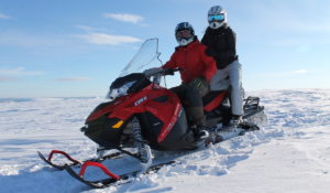 Ett par på snöskoter i svenska fjällen