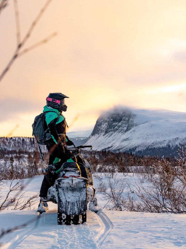 Person på snöskoter i solnedgång i Borgafjäll