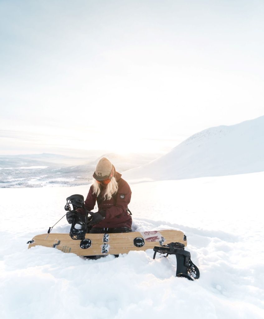 Person som fixar med snowboarden i vinterlandskap